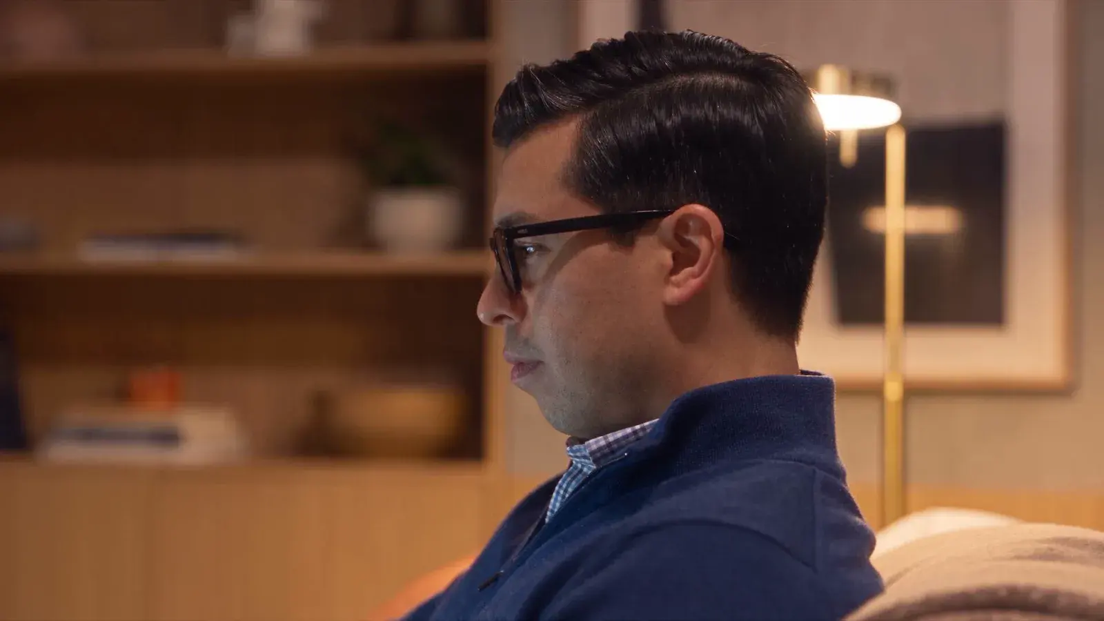 AI-generated sample by TCV Studio. A man with glasses is shown in profile in a warm interior.